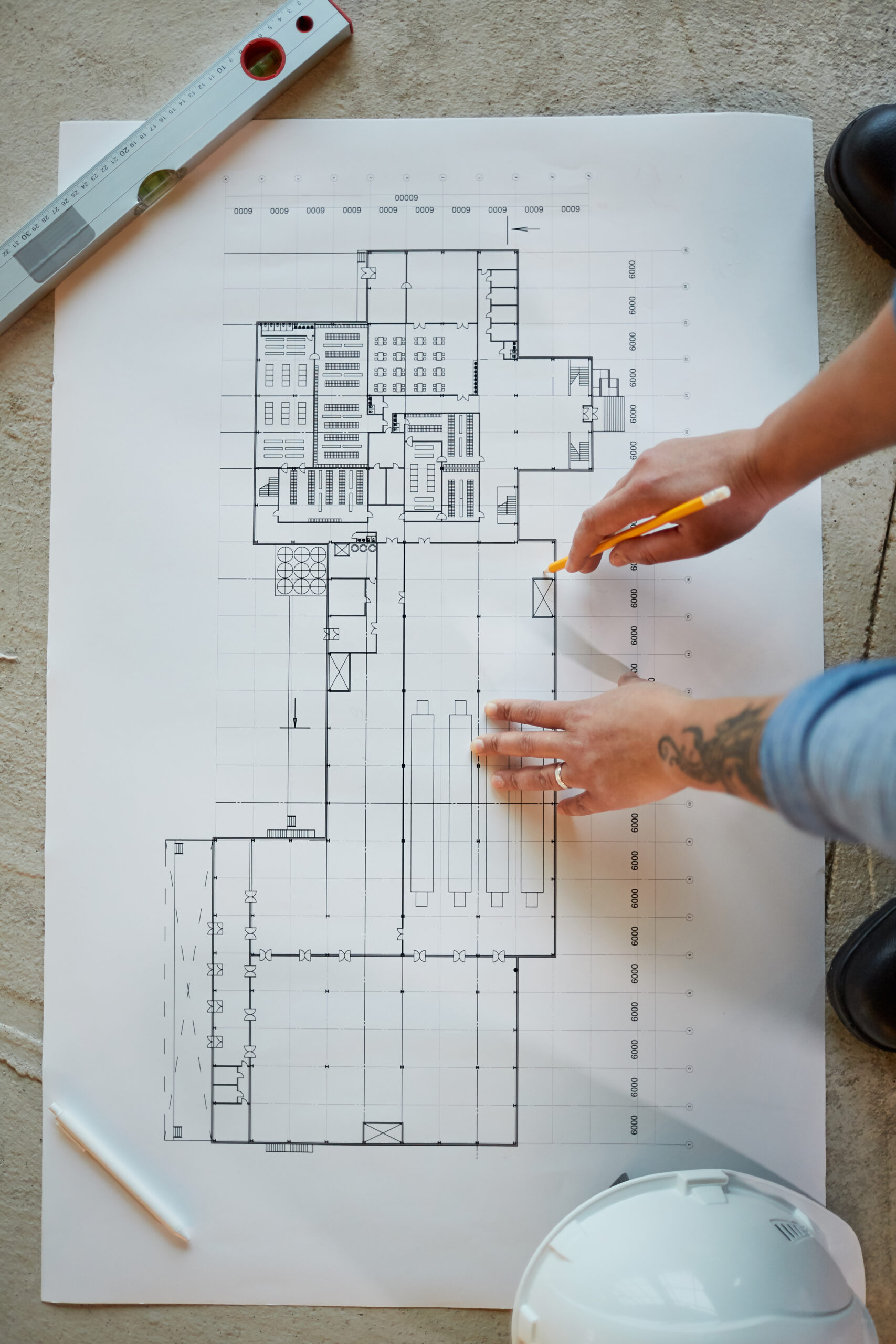 Top view close up of female construction worker pointing at blueprints while working in apartment building, copy space
